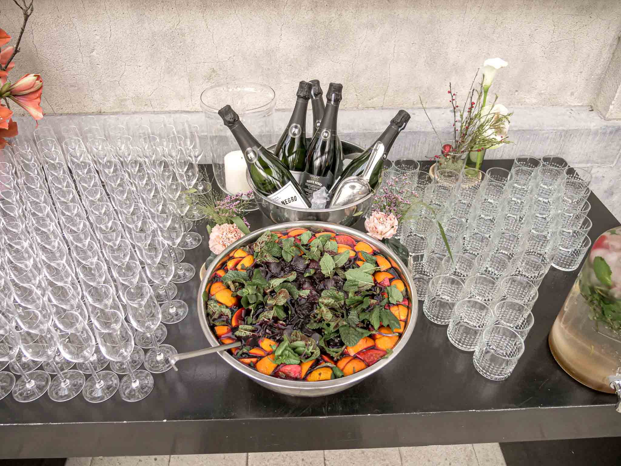 Tafel met verschillende soorten lege glazen, een schaal met glühwein en gekoelde champagneflessen.