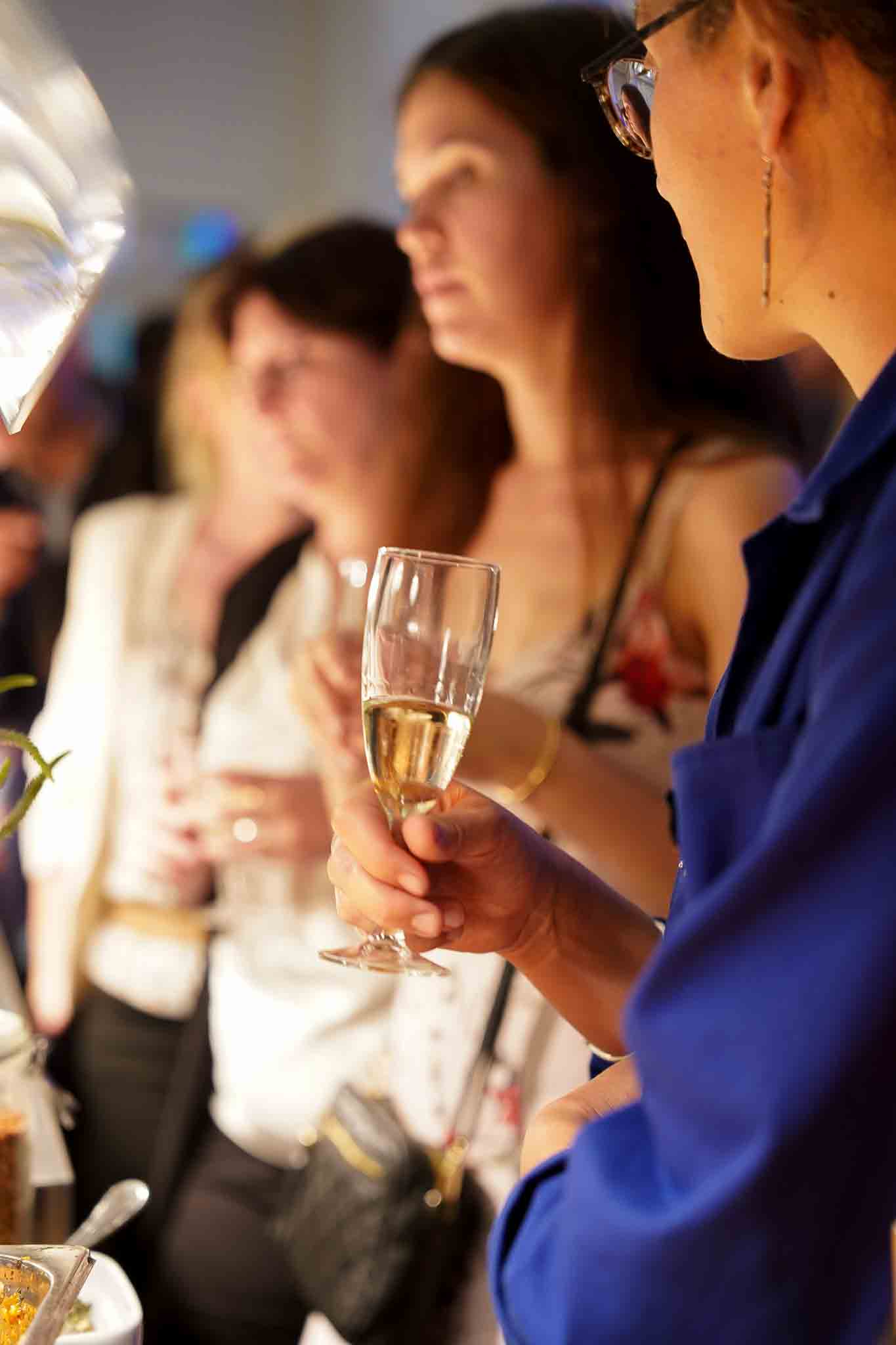 Klanten staan te praten met een glas champagne in hun handen.